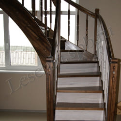 Фотография лестницы из массива сосны с двухцветной тонировкой и лаковым покрытием, закрытая, с пригласительной ступенью с гнутым подступенком